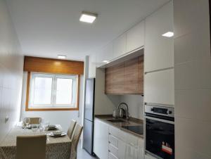 a kitchen with white cabinets and a table with a dining room at Piso vacacional acogedor in A Coruña