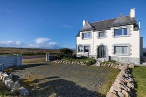 a white house with a stone fence in front of it at La Villa de Pascal, vue mer in Penmarch