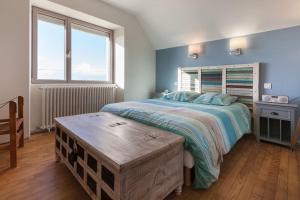 a bedroom with a large bed and a wooden table at La Villa de Pascal, vue mer in Penmarch