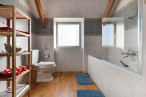 een badkamer met een bad, een toilet en een raam bij La Villa de Pascal, vue mer in Penmarcʼh
