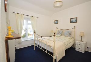 ein Schlafzimmer mit einem Himmelbett und einem Fenster in der Unterkunft Charnwood Cottage in Brading