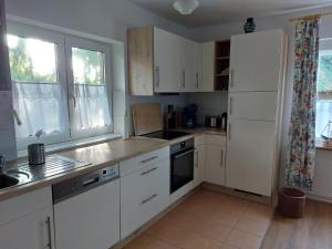 eine Küche mit weißen Schränken und weißen Geräten in der Unterkunft Ferienwohnung zwischen Deich und Düne in Dierhagen