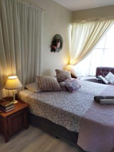 a bedroom with a bed with two lamps and a window at Aan die Voet van die Magalies in Pretoria