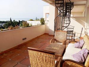 a patio with chairs and a couch on a balcony at Apartamento Atico Duplex HOTEL Guadalpin Marbella in Marbella
