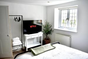 a bedroom with a bed and a tv and a window at Angel Cottage in Bishopsteignton