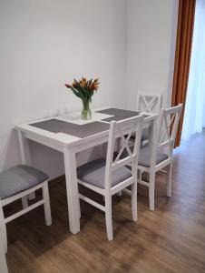 una mesa blanca con sillas y un jarrón con flores en Apartament Sunset Leszno, en Leszno