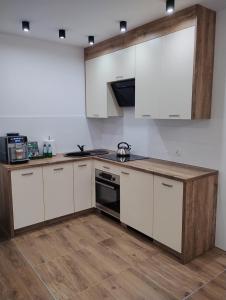a kitchen with white cabinets and a stove top oven at Apartament Sunset Leszno in Leszno