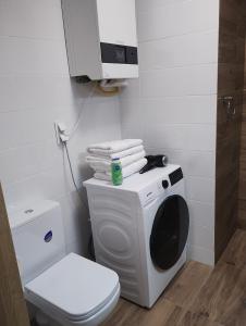 a bathroom with a toilet and a washing machine at Apartament Sunset Leszno in Leszno