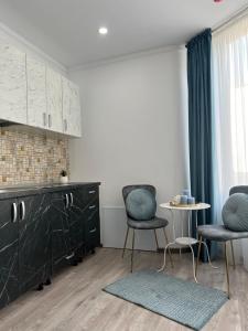a kitchen with black cabinets and two chairs and a table at Cloud 9 Studios in Piatra Neamţ