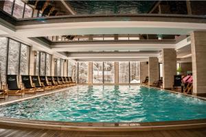 een groot zwembad in een gebouw met stoelen bij Apartman Laura Milmari Resort in Kopaonik