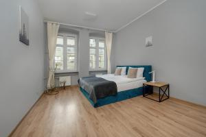 - une chambre avec un lit avec une couverture bleue et 2 fenêtres dans l'établissement Spacious 3-Bedroom Apartment Plac Grunwaldzki Wrocław by Renters, à Wrocław