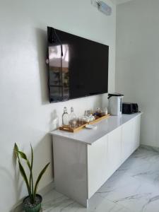 a kitchen with white cabinets and a flat screen tv at Empyrean Stay, Maldives in Thulusdhoo