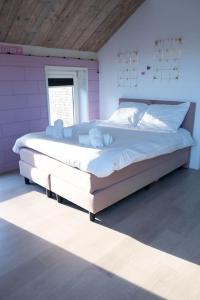 uma grande cama branca num quarto com uma janela em Luxury home Egmond em Egmond aan Zee