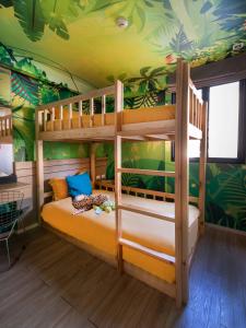 a bedroom with two bunk beds in a room with tropical wallpaper at Cross Vibe Bangkok Sukhumvit in Bangkok