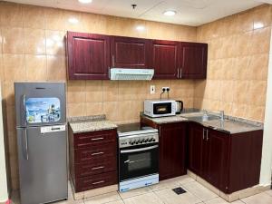 a kitchen with wooden cabinets and a stove and refrigerator at Nahda Star Residence - Home Stay in Dubai
