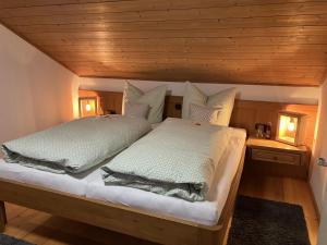 - une chambre avec un lit doté de draps et d'oreillers blancs dans l'établissement Ferienhaus Kögel, à Nesselwang
