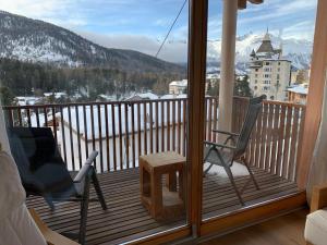 a room with a balcony with a chair and a table at Chesa Chavriol in Pontresina