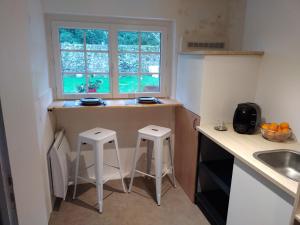 a kitchen with two stools and a counter with a window at Ty Nid in Ploemel