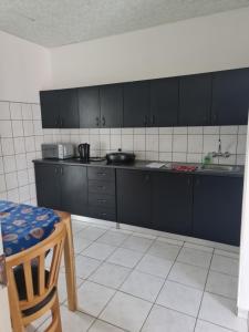 a kitchen with black cabinets and a white tile floor at Villa Saffier in Windhoek