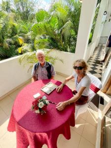 un hombre y una mujer sentados en una mesa rosa en Dad's Holiday Home, en Matale