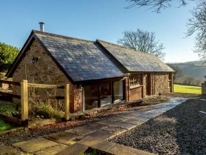 una pequeña casa de piedra con una valla de madera en 2 Bed in South Molton 86642, en Knowstone
