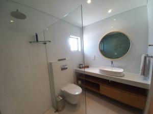 a bathroom with a toilet and a sink and a mirror at Queens Cove Apt 3 in Knysna