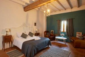 a bedroom with a bed and chairs and a chandelier at Le Mas de la Prade in Bages