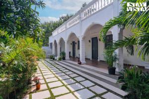 an empty courtyard of a white building with plants at StayVista at Agam Villa Mahabalipuram in Chennai