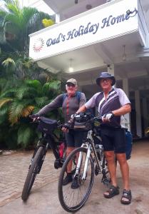 dois homens de pé com as suas bicicletas em frente a um edifício em Dad's Holiday Home em Matale