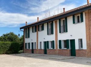 un edificio de ladrillo con puertas y ventanas verdes en Canovetta Country House "Jakiro" - nearby Cremona, 