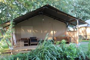 einen Pavillon mit Stühlen und Tischen auf einem Feld in der Unterkunft Luxe safaritent aan het water in Hommerts