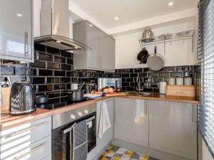 a kitchen with stainless steel appliances and black tiles at 2 Bed in Lyndhurst 86768 in Lyndhurst