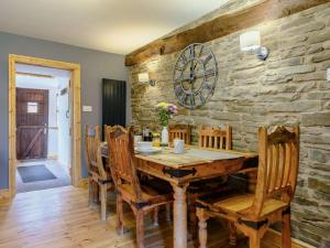 a dining room with a wooden table and a stone wall at 1 Bed in Longtown 88510 in Llanveynoe