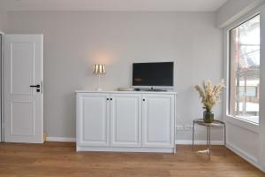 uma sala de estar branca com uma televisão num armário branco em Alice, Whg 9, 1 OG em Westerland