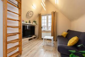 a living room with a couch and a tv at Old Town Studio with Mezzanine in Gdańsk