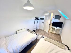 een kamer met 2 bedden en een bureau met een computer bij Angel Cottage in Bishopsteignton