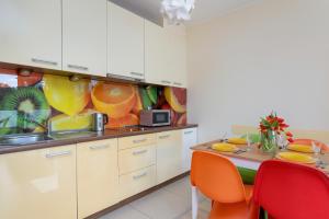 a kitchen with white cabinets and a table with red chairs at Lilly Aquamarina SeaView by Rent like home in Międzyzdroje