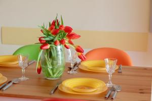a table with a vase with red tulips in it at Lilly Aquamarina SeaView by Rent like home in Międzyzdroje