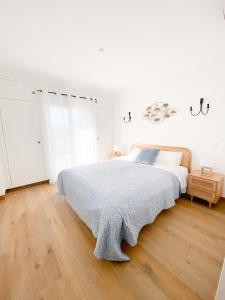 a white bedroom with a bed and a wooden floor at Casa Rostam - Duplex avec Terrasses - Ferragudo in Ferragudo