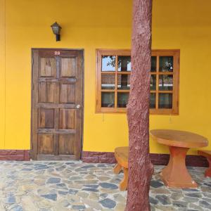 a yellow building with a wooden door and a table at โรงแรมวรรณิดา การ์เด้น รีสอร์ท in Ban Dong Hua Khot (1) +12 photos
