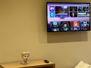 a tv on a wall with a statue on a table at Arial Lofts in Vlorë