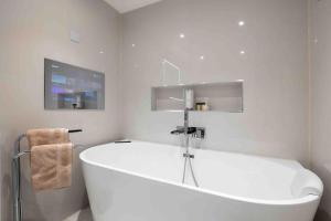 a white bathroom with a large tub and a tv at Wanstead, Escape London in London-Luxury 2 Bed in London