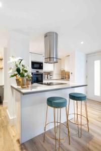 a kitchen with two stools sitting at a counter at Wanstead, Escape London in London-Luxury 2 Bed in London