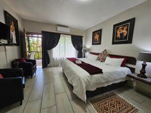 een slaapkamer met een groot bed en een woonkamer bij Ndiza Lodge and Cabanas in St Lucia