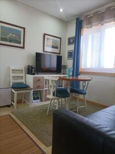 ein Wohnzimmer mit einem Tisch und einem TV in der Unterkunft SBT Sun Beach Terrace "The best house" in Figueira da Foz