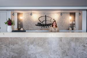 a woman standing behind a counter in a lobby at Pedi Beach Hotel in Symi