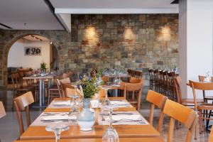 a dining room with tables and chairs and a brick wall at Pedi Beach Hotel in Symi