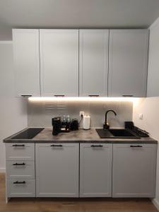 a kitchen with white cabinets and a sink at Slate Apartament Polanica - Zdrój in Polanica-Zdrój