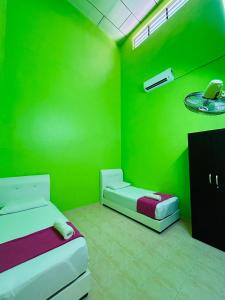 a room with two beds and a green wall at Sena Yang Indah Homestay in Kangar