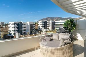 una silla en el balcón con vistas a los edificios en HigueronRentals Twin apartments, en Málaga